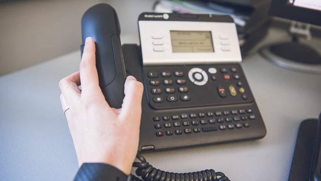 Hand hält Hörer vom Telefon